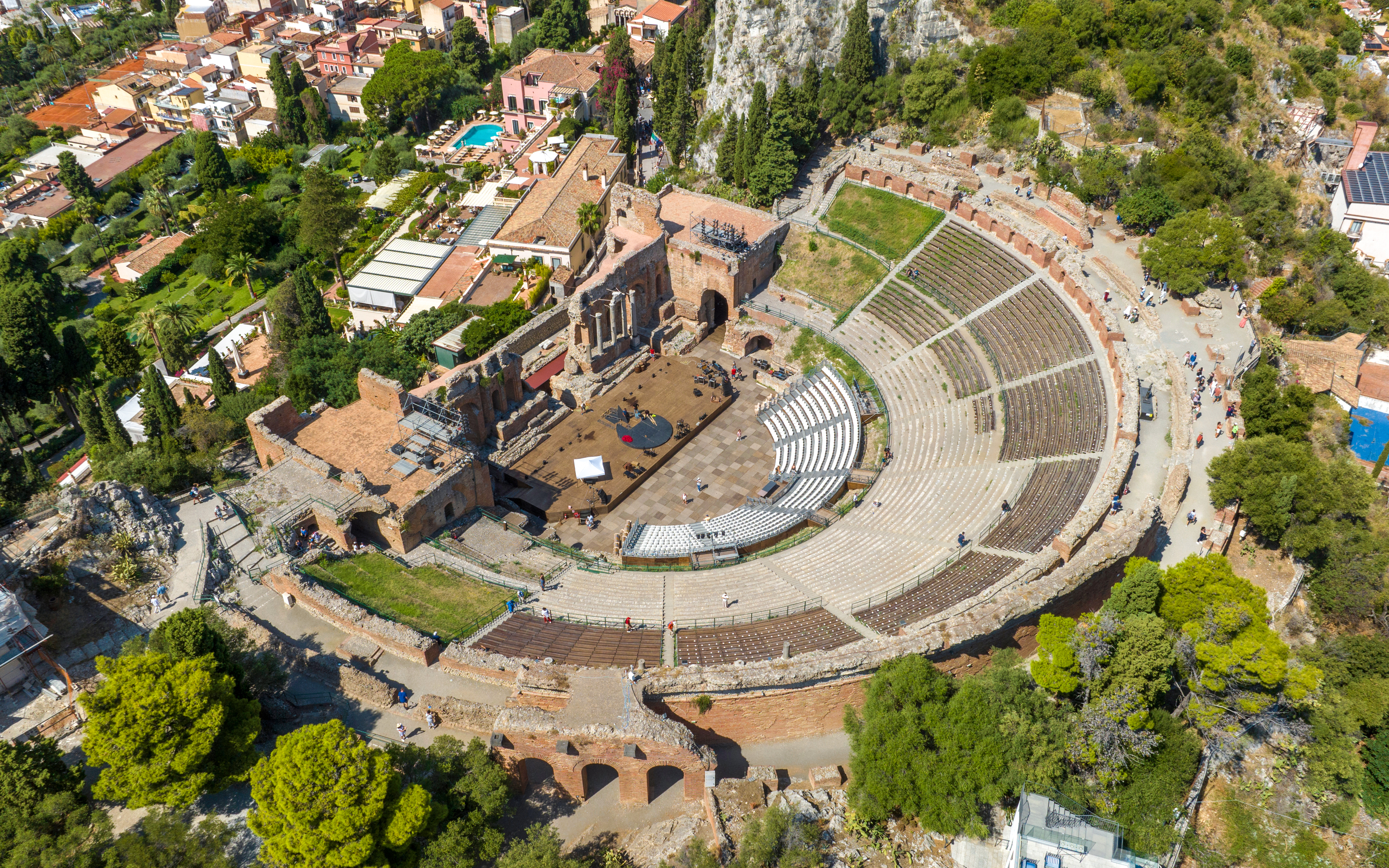 Aerial view of the ancient theatre of Taormina, surrounded by greenery and buildings, Sicily, Italy.
