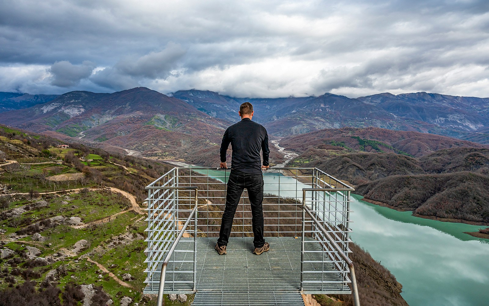 Guest overlooking Bovilla Lake from a viewing platform, surrounded by mountains.