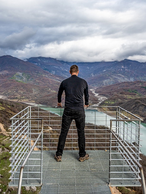 Guest overlooking Bovilla Lake from a viewing platform, surrounded by mountains.
