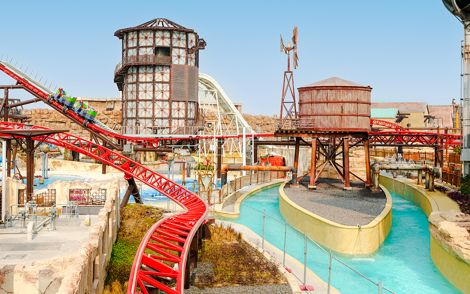 Action River and roller coaster at Meryal Waterpark with industrial-themed structures.