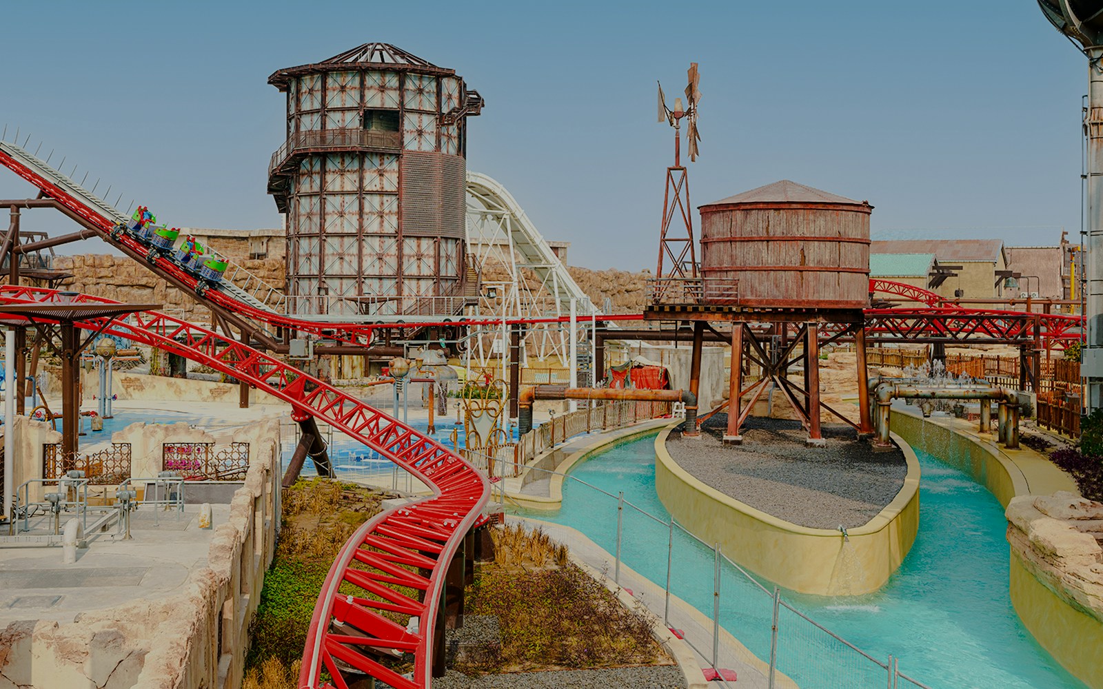 Action River and roller coaster at Meryal Waterpark with industrial-themed structures.