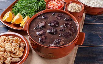 Feijoada with rice, greens, oranges, and farofa on Rio de Janeiro food tour.