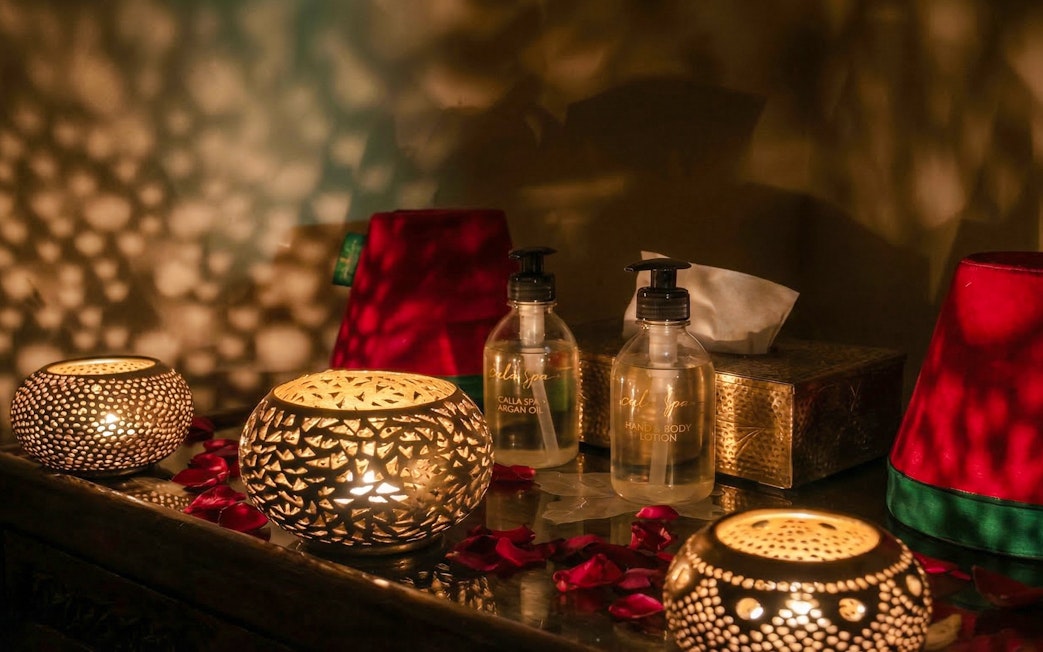 Moroccan hammam setting with candles, argan oil, and rose petals.