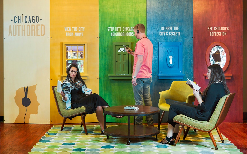 Chicago exhibit with visitors engaging in interactive displays and reading, promoting city exploration.