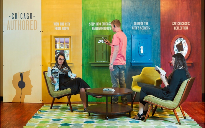 Chicago exhibit with visitors engaging in interactive displays and reading, promoting city exploration.