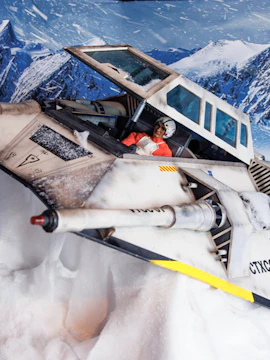 Pilot in a Star Wars snowspeeder at snowy exhibition display.