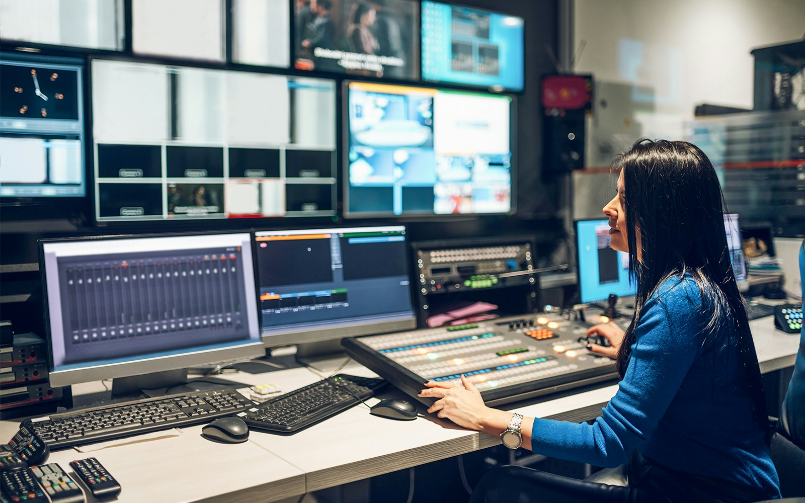 Broadcast technician operating control panel in a TV studio.