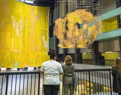 Visitors observing large art installations at Tate Modern, London.