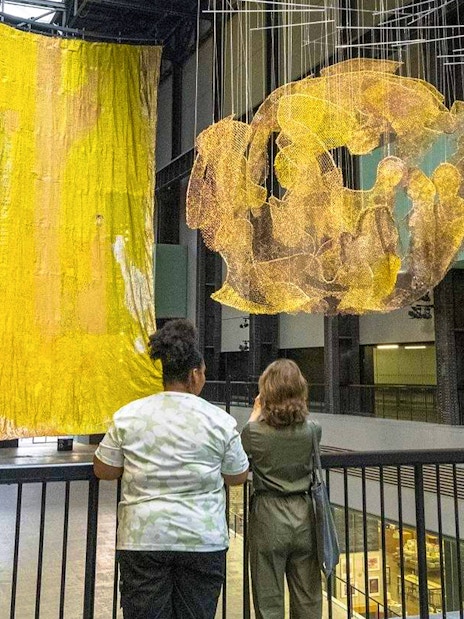 Visitors observing large art installations at Tate Modern, London.