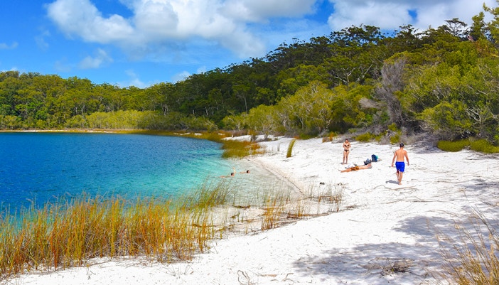 Visitors enjoying the white sandy beach and clear waters of Lake McKenzie, Fraser Island, K'gari.