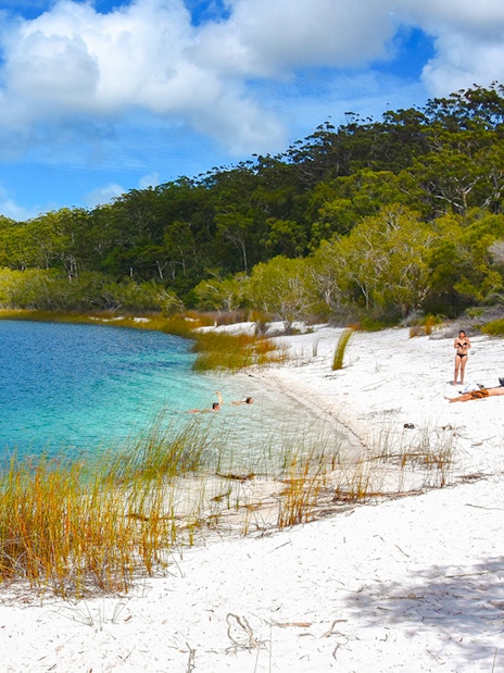 Visitors enjoying the white sandy beach and clear waters of Lake McKenzie, Fraser Island, K'gari.