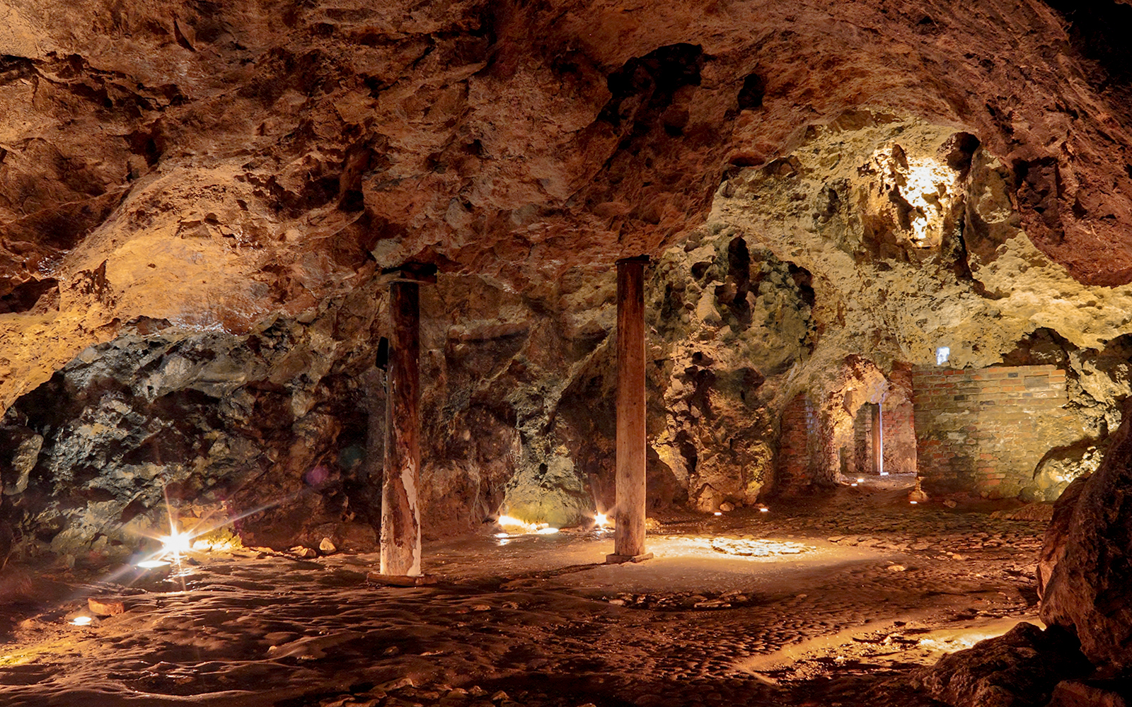 Underground cave with stone pillars and illuminated pathways in Naples, Italy.