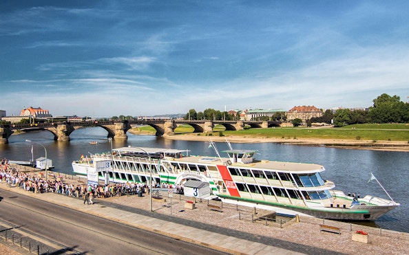Elbe river cruise ship docked in Dresden with Augustus Bridge in the background.