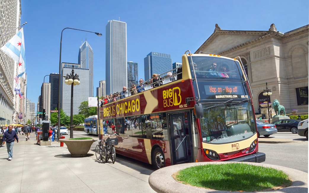Big Bus Chicago tour passing by the Art Institute with city skyline in the background.