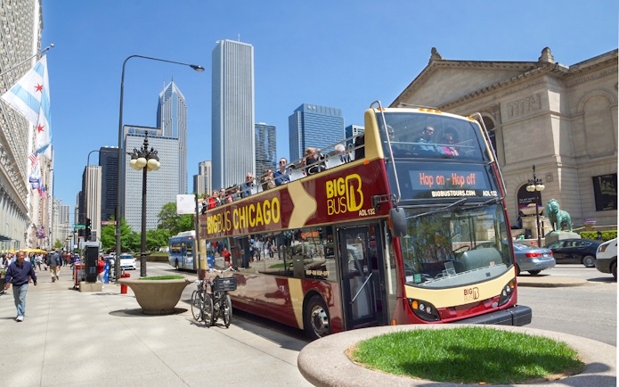 Big Bus Chicago tour passing by the Art Institute with city skyline in the background.