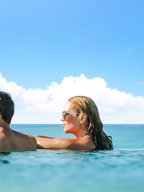 Guests relaxing in an infinity pool overlooking the ocean.