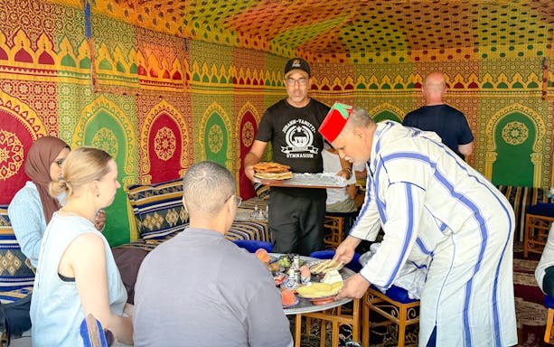 Man serving traditional Berber breakfast in colorful caidal tent, Marrakech.