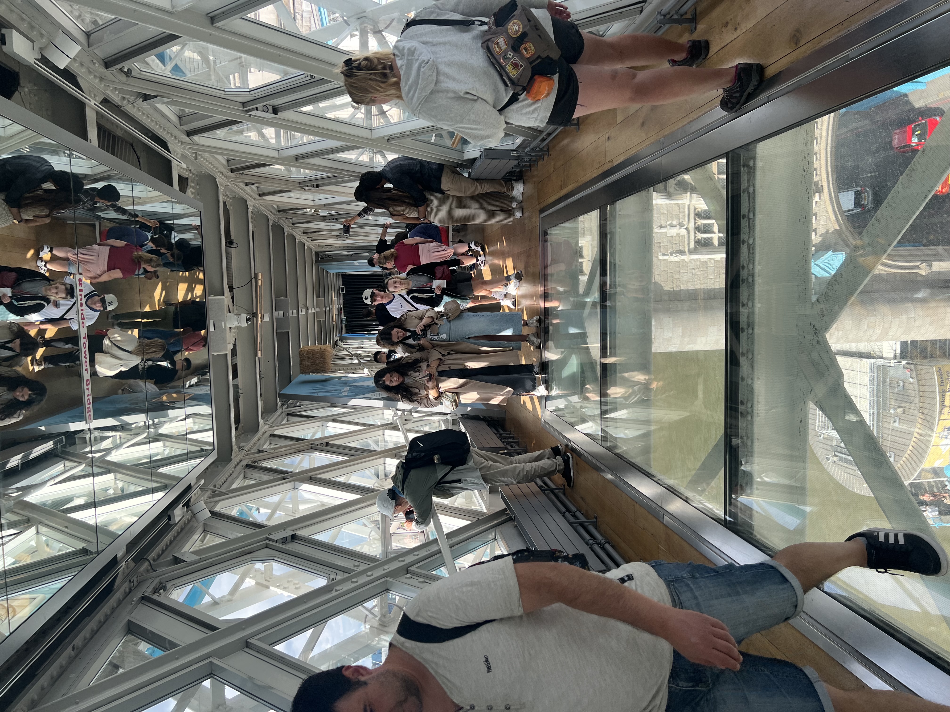 Visitors walking on the glass walkway inside Tower Bridge, London.