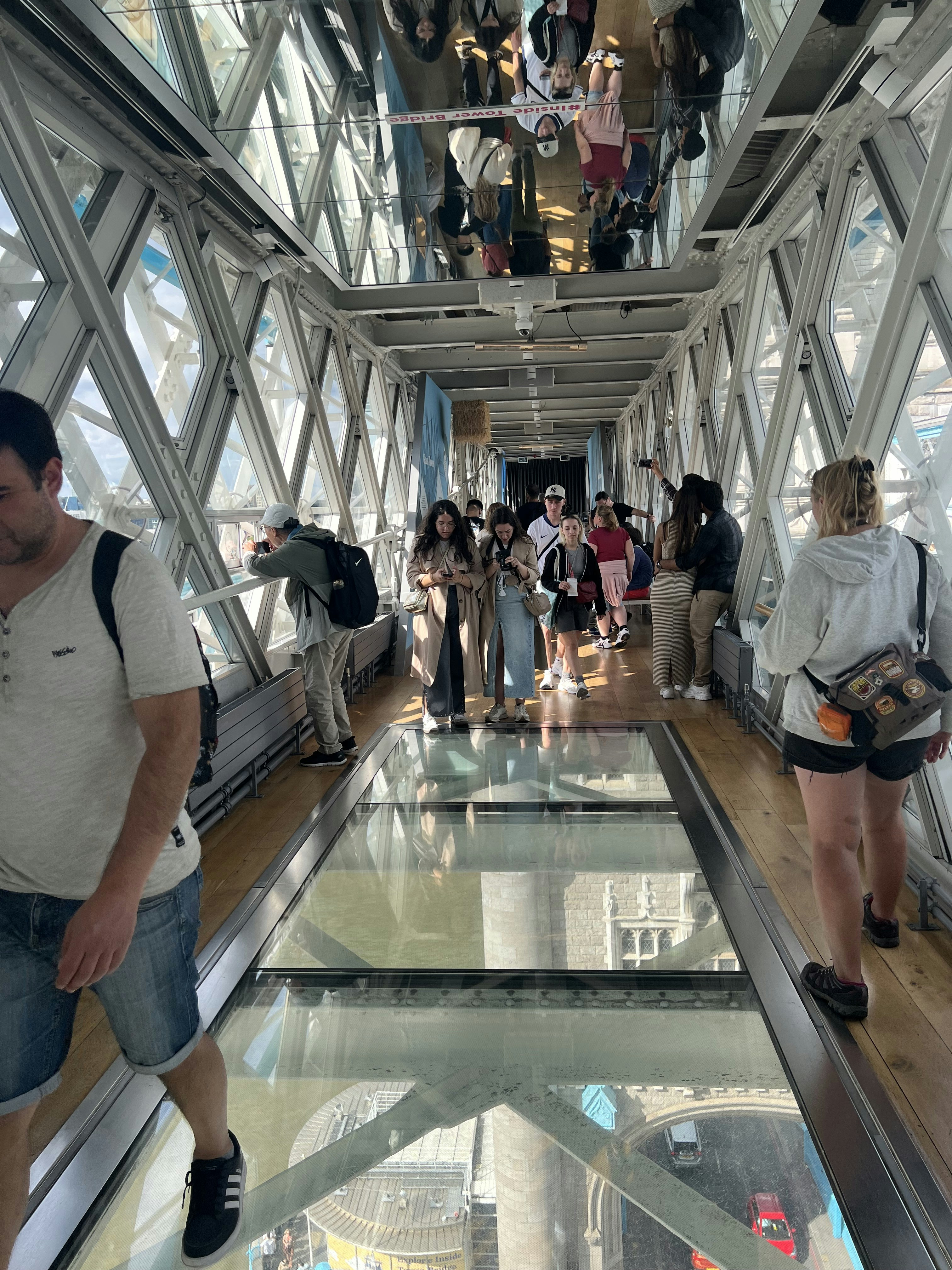Visitors walking on the glass walkway inside Tower Bridge, London.
