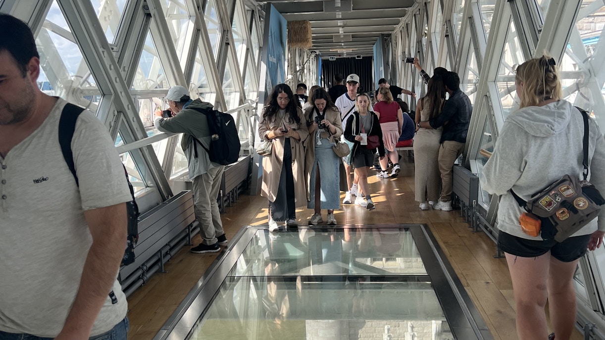 Visitors walking on the glass walkway inside Tower Bridge, London.