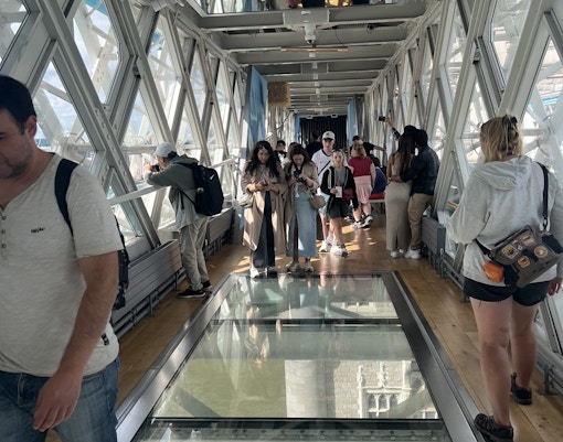 Visitors walking on the glass walkway inside Tower Bridge, London.
