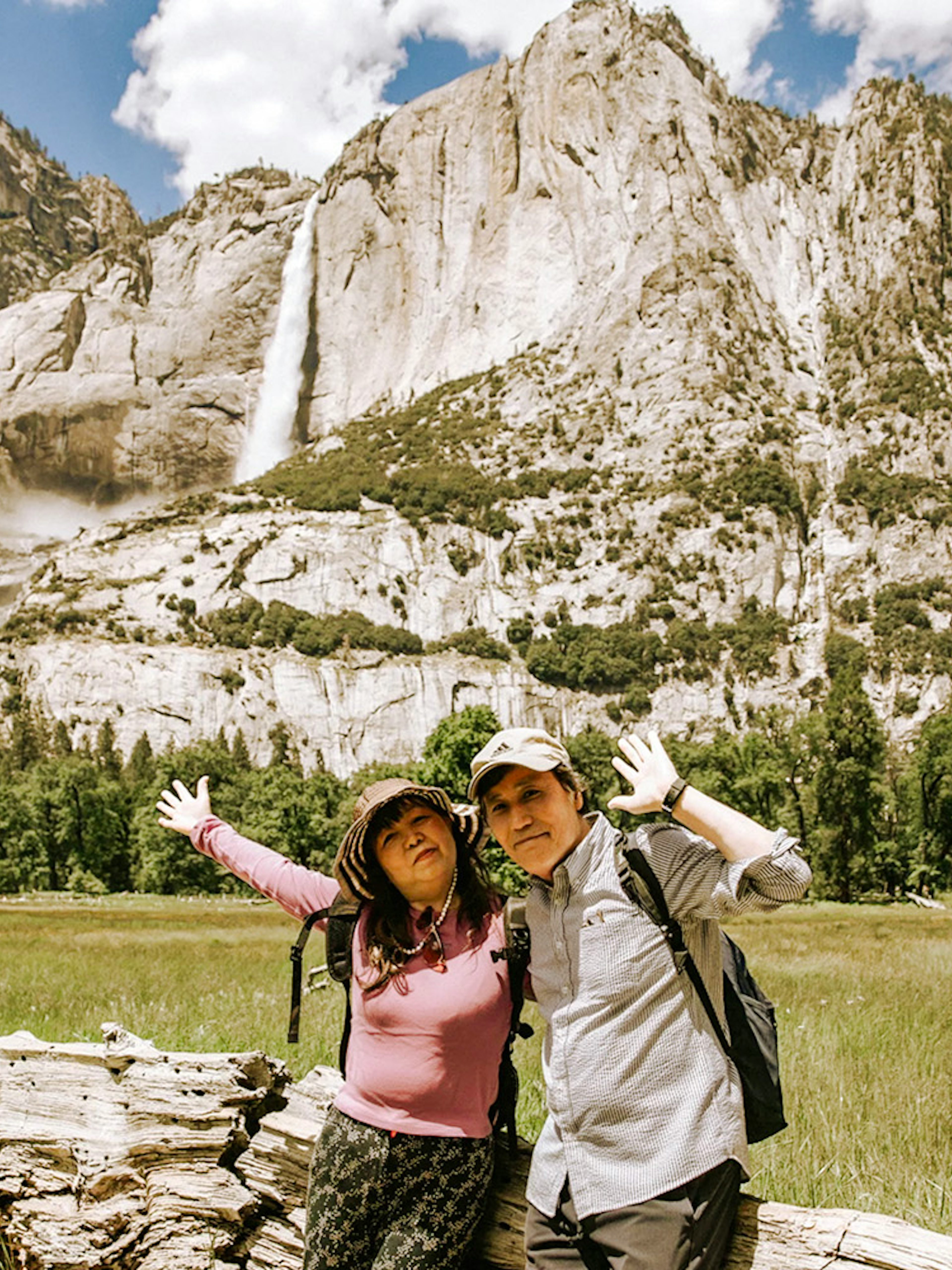 Visitors posing in front of a waterfall at Yosemite National Park, California.