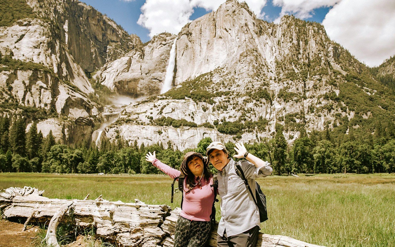 Visitors posing in front of a waterfall at Yosemite National Park, California.