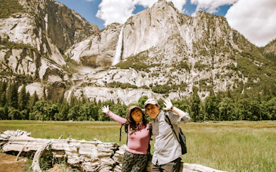 Visitors posing in front of a waterfall at Yosemite National Park, California.