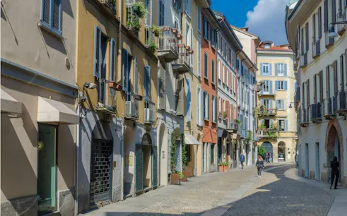Street view of colorful buildings in Milan's Brera district, part of a self-guided city exploration game.
