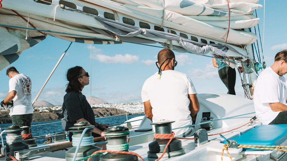 Tourists on a private sailboat tour for dolphin watching near coastal cliffs.