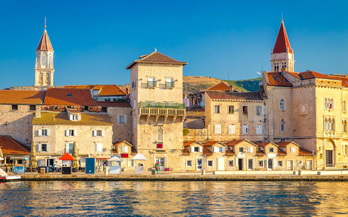Promenade along the waterfront in the Old Town of Trogir, Croatia, with historic buildings.