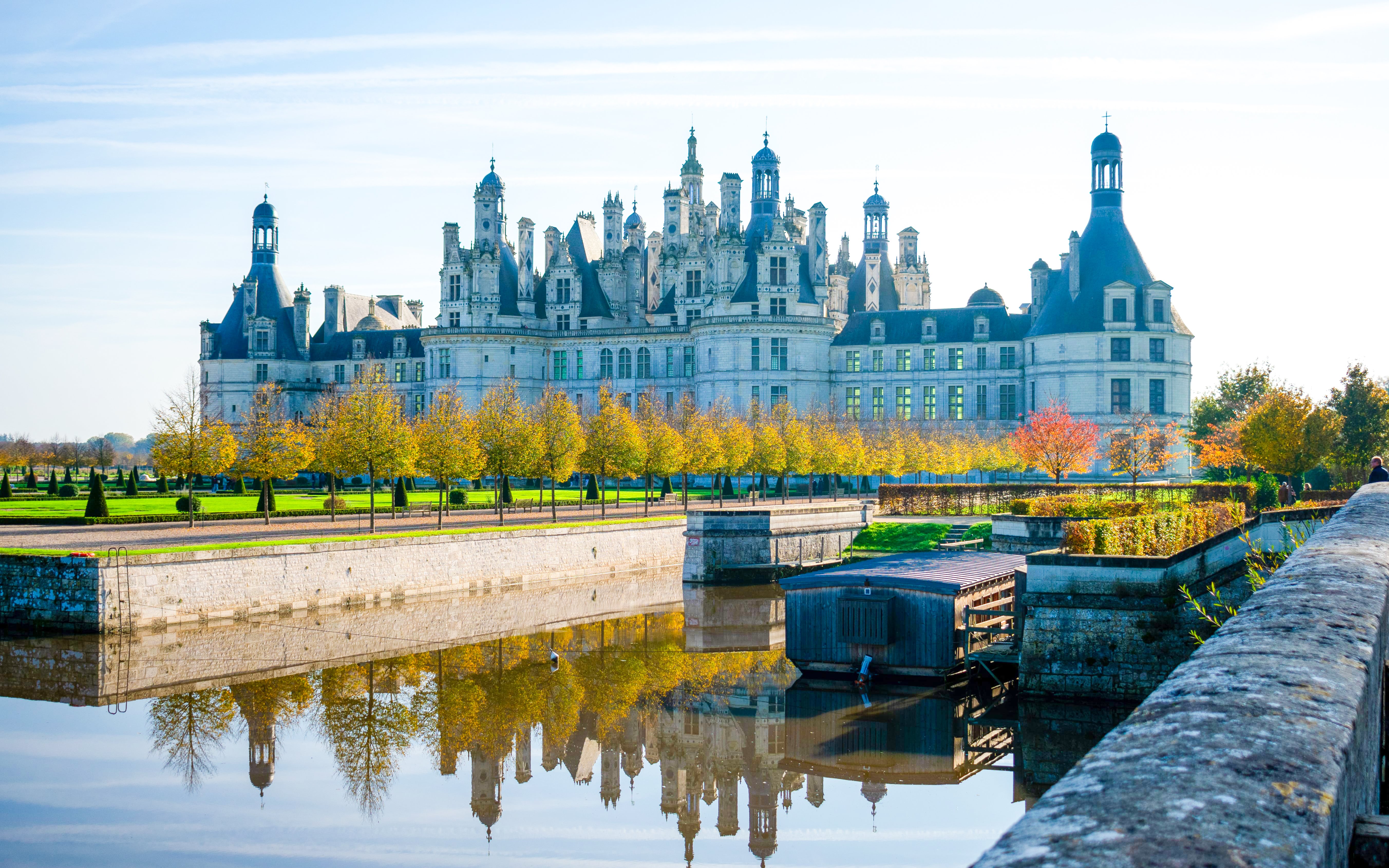 Chambord Castle in France with reflection in the water and autumn trees.