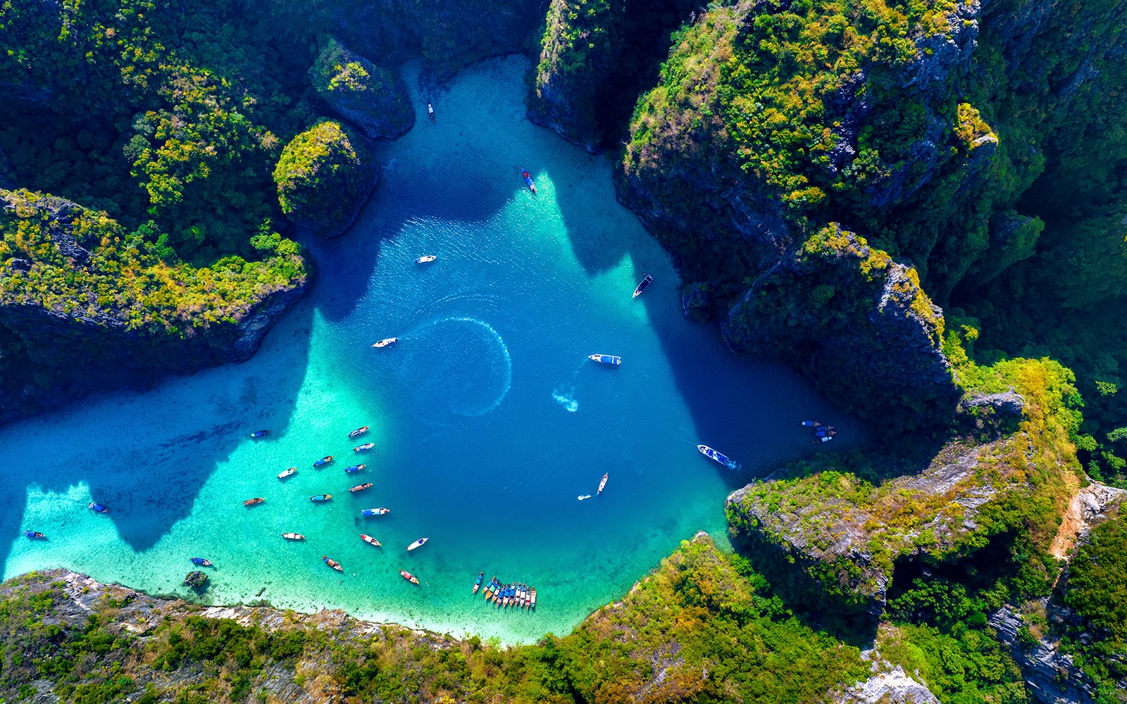 Aerial view of Pileh Lagoon's emerald waters surrounded by limestone cliffs and boats.
