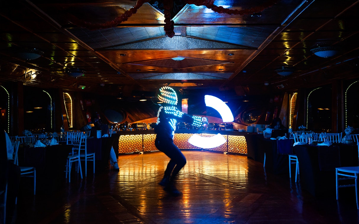 Performer in LED suit dancing on Dubai Marina luxury dhow cruise.