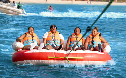 Group enjoying a donut ride on the ocean, wearing life jackets.