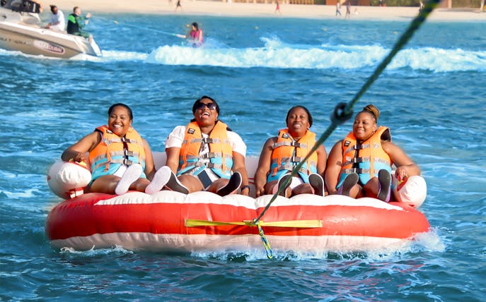 Group enjoying a donut ride on the ocean, wearing life jackets.