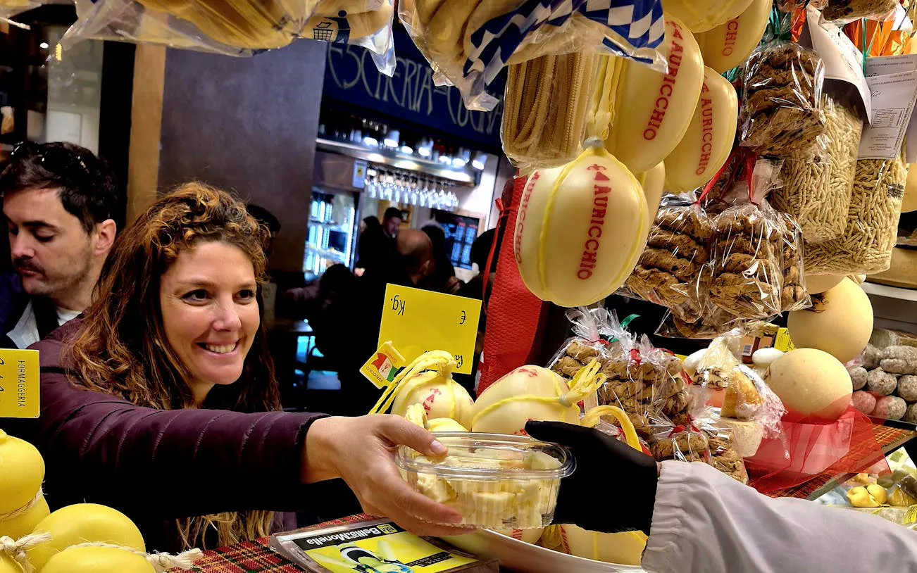 Customer sampling cheese at Padova market stall during food tour.