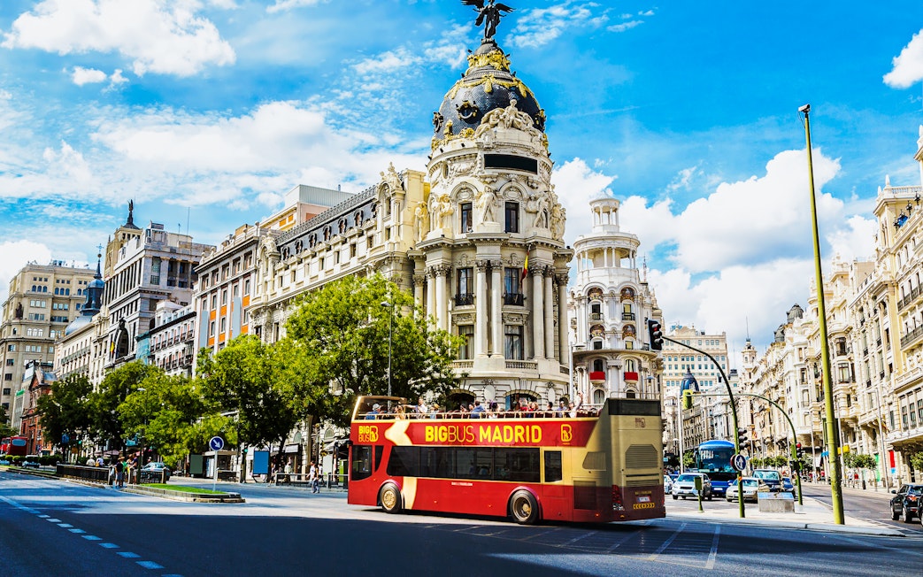 Open-top tour bus in front of Metropolis Building, Madrid.
