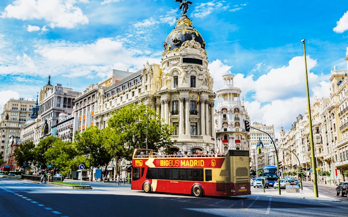 Open-top tour bus in front of Metropolis Building, Madrid.