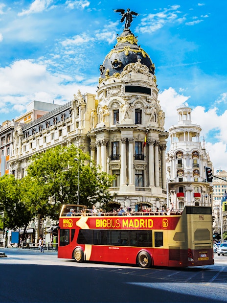 Open-top tour bus in front of Metropolis Building, Madrid.