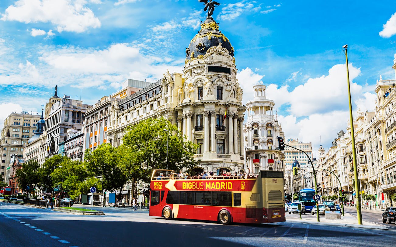 Open-top tour bus in front of Metropolis Building, Madrid.