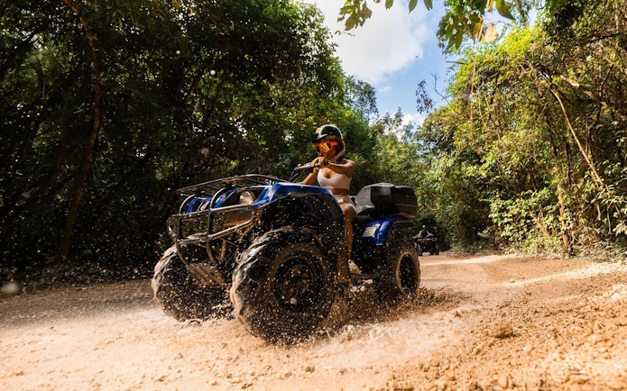 ATV rider navigating a muddy jungle trail in Cancun.