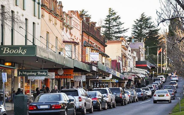 Shops and parked cars along a bustling street in Leura Village, Australia.