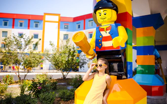 Child posing with large Lego figure at Legoland New York.