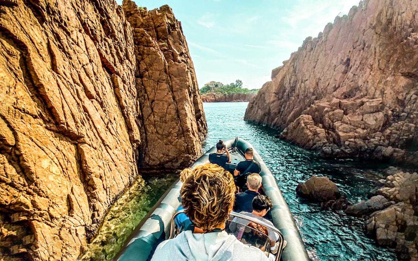 Boat navigating between rocky cliffs in Estérel Natural Park near Cannes.