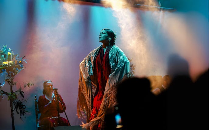 Flamenco dancer performing on stage in Barcelona with a singer in the background.