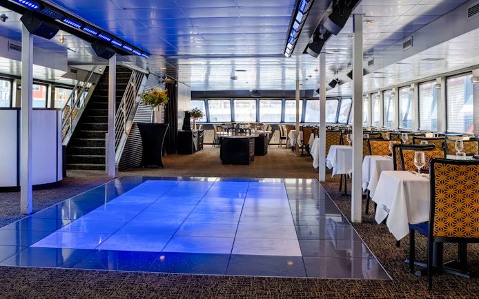 Interior of New Jersey Signature Cruise ship with dining tables and dance floor.