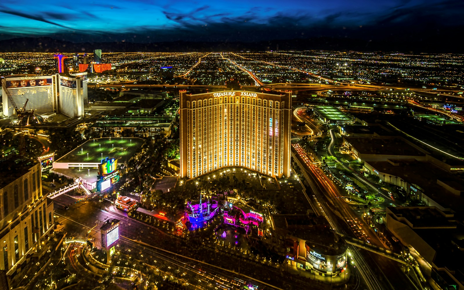 Aerial view of Las Vegas Strip at night with Treasure Island Hotel and Casino illuminated.