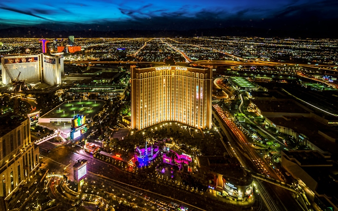 Aerial view of Las Vegas Strip at night with Treasure Island Hotel and Casino illuminated.