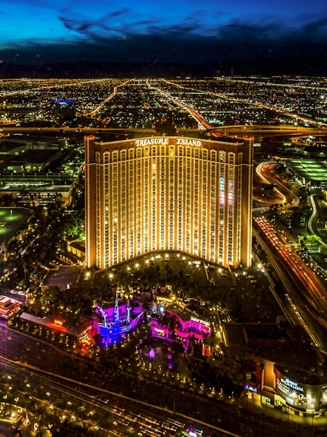 Aerial view of Las Vegas Strip at night with Treasure Island Hotel and Casino illuminated.